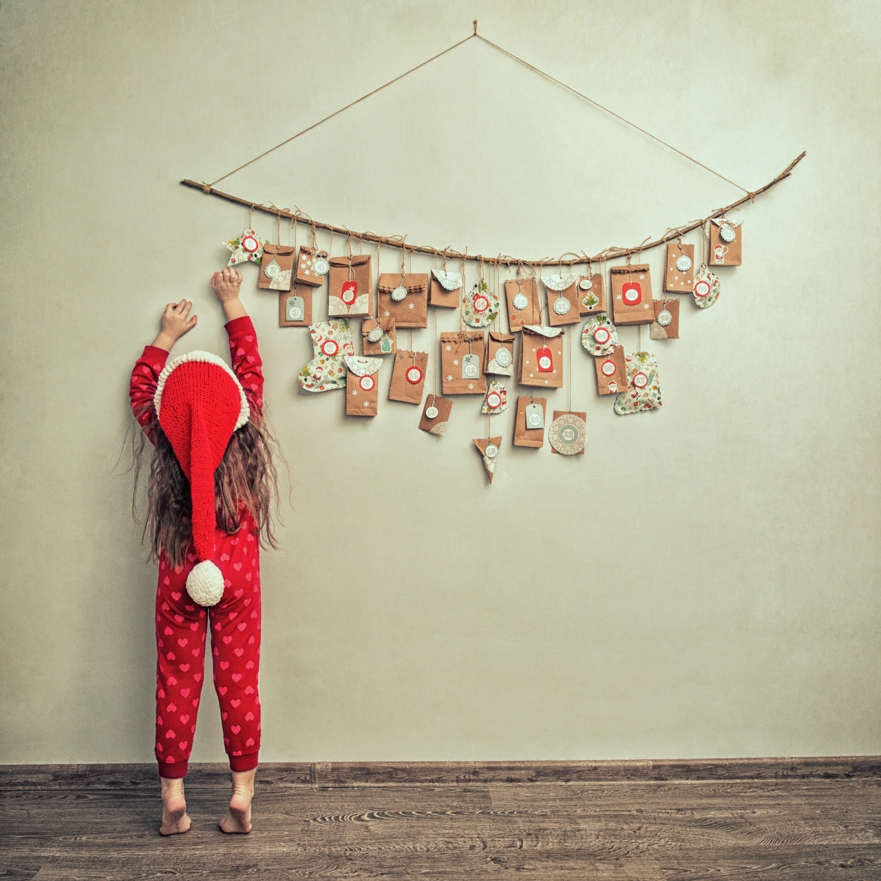 jente i nissedrakt strekker seg etter gave i adventskalender 
